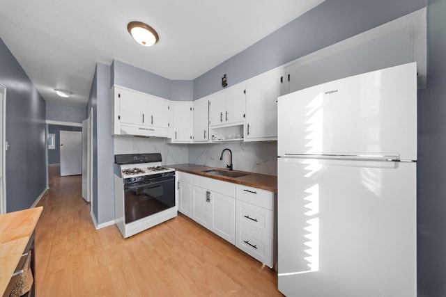 kitchen with white appliances, light wood-style flooring, a sink, under cabinet range hood, and white cabinetry