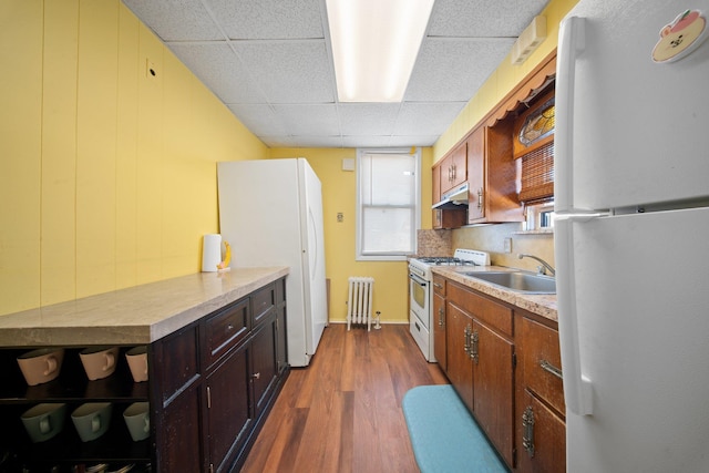 kitchen featuring white appliances, radiator, a sink, light countertops, and under cabinet range hood