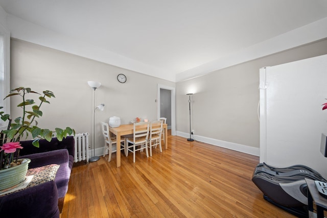 dining space featuring baseboards, light wood-style floors, and radiator heating unit