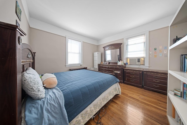 bedroom with cooling unit and light wood finished floors