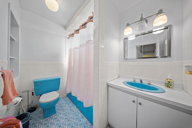 bathroom featuring wainscoting, tile walls, vanity, and toilet