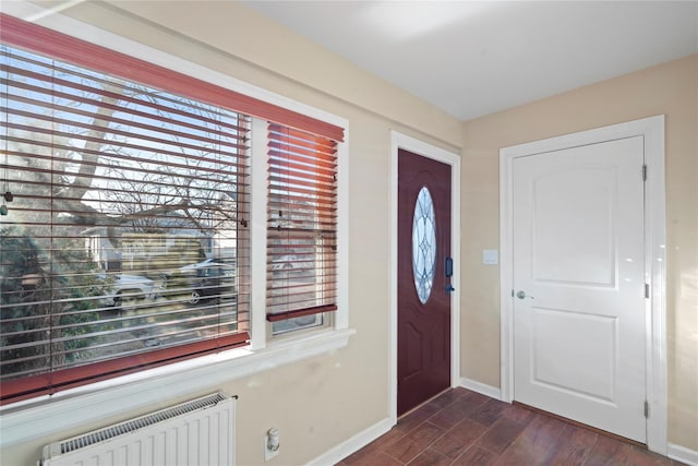 entryway with dark wood finished floors, radiator heating unit, and baseboards