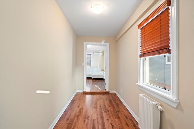 hall featuring a wealth of natural light, radiator, baseboards, and wood finished floors