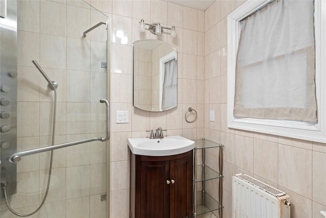 full bathroom featuring vanity, tile walls, radiator, and a stall shower