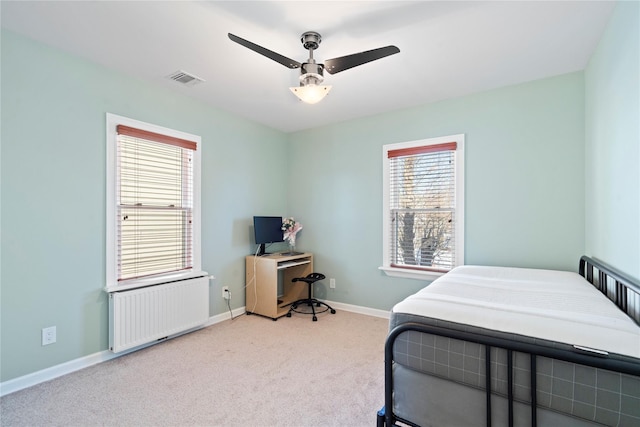 carpeted bedroom with visible vents, radiator heating unit, a ceiling fan, and baseboards