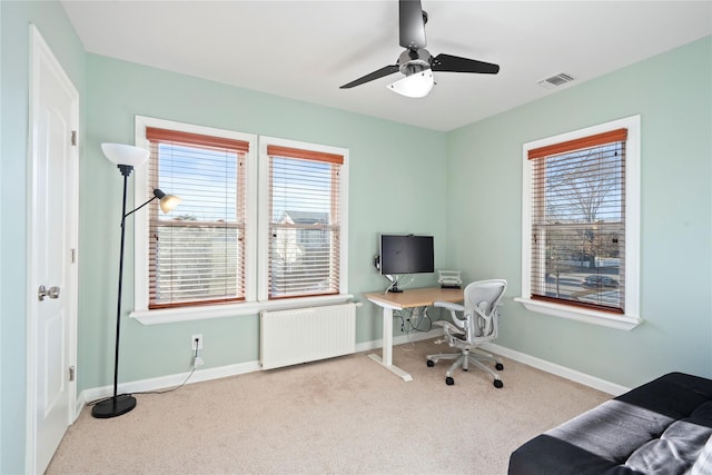 office featuring a ceiling fan, carpet, visible vents, baseboards, and radiator heating unit