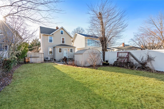 rear view of house featuring a lawn, a chimney, a fenced backyard, and an outdoor structure