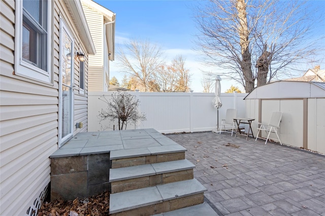 view of patio / terrace with an outbuilding, a shed, and a fenced backyard