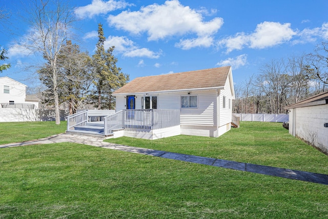 rear view of property with a lawn, roof with shingles, a deck, and fence