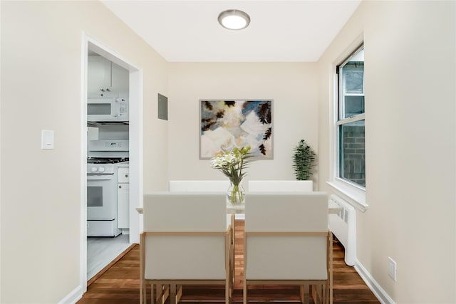 dining area with baseboards and dark wood-type flooring