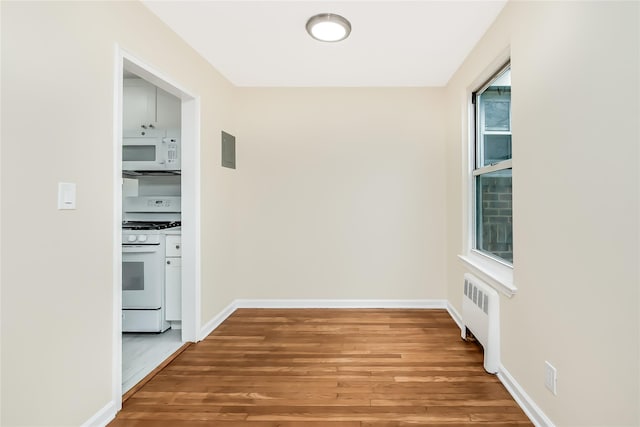 hall featuring radiator, baseboards, and wood finished floors