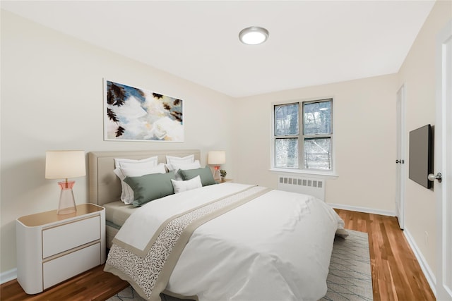 bedroom featuring radiator, wood finished floors, and baseboards