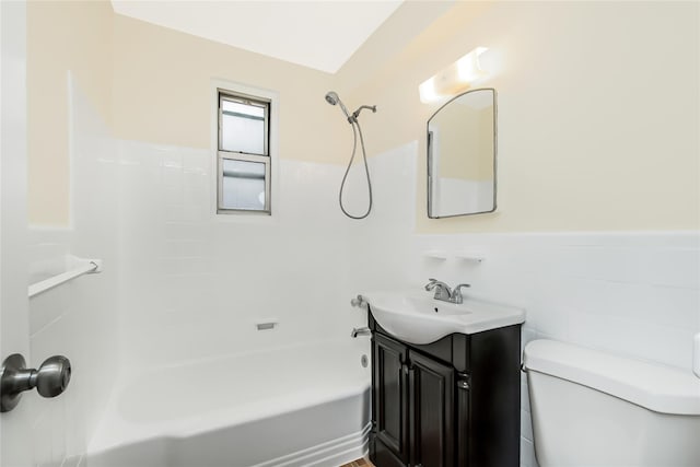 bathroom featuring toilet, tile walls, wainscoting, tub / shower combination, and vanity