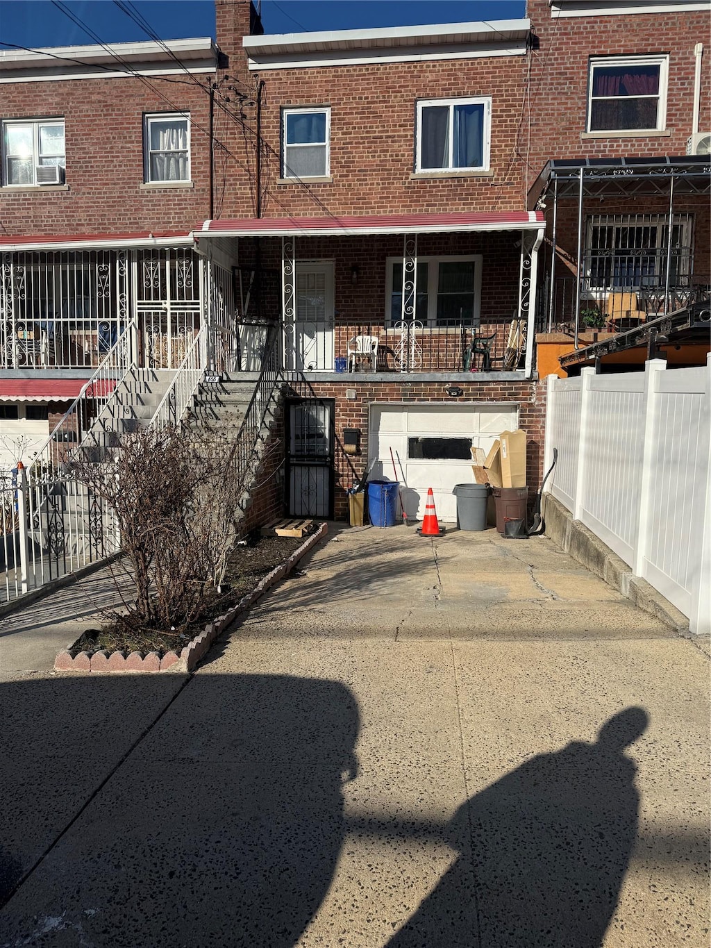 back of house with stairway, fence, driveway, a garage, and brick siding