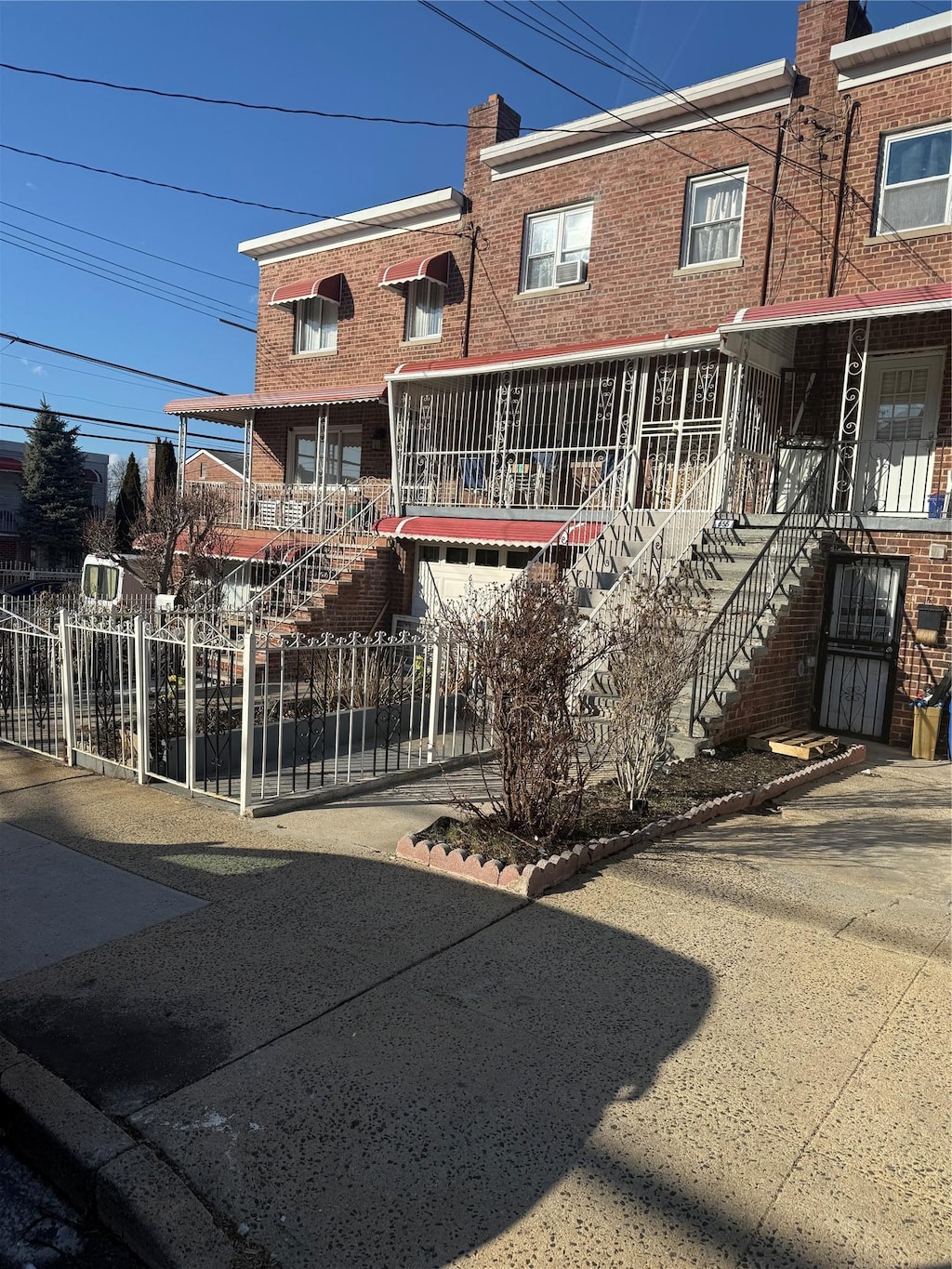 multi unit property featuring stairway, brick siding, a chimney, and fence