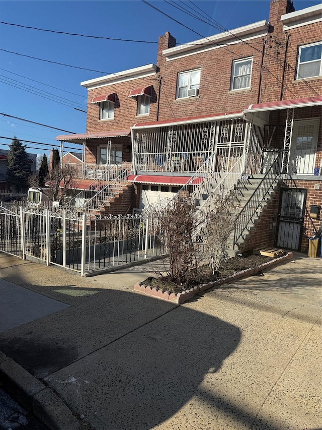 multi unit property featuring stairway, brick siding, a chimney, and fence