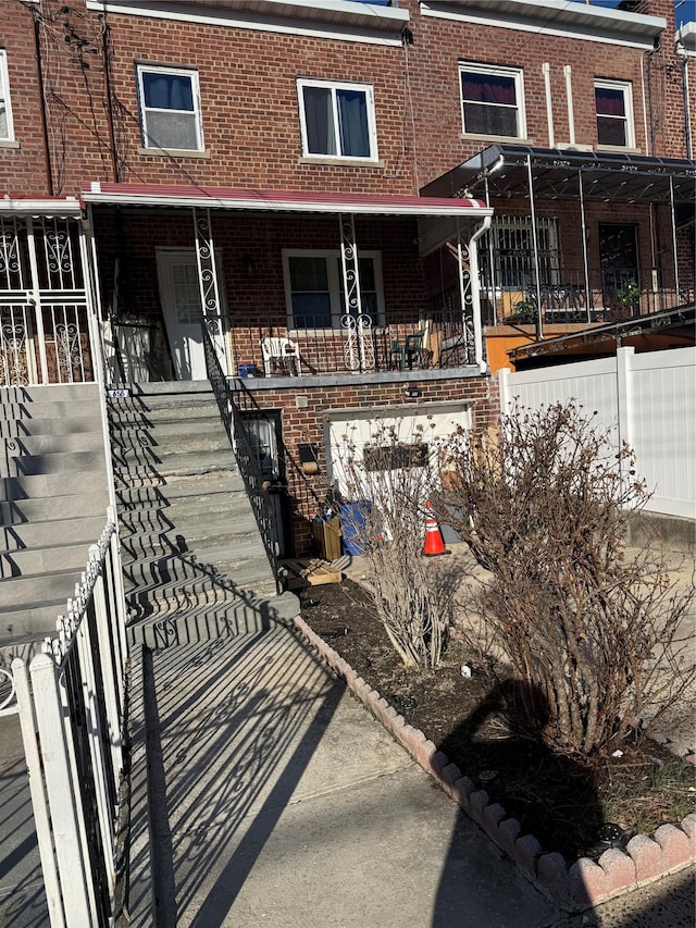 view of front of home with brick siding, covered porch, and stairs