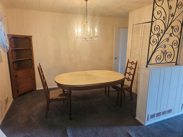 dining space with a notable chandelier, visible vents, wooden walls, and carpet floors