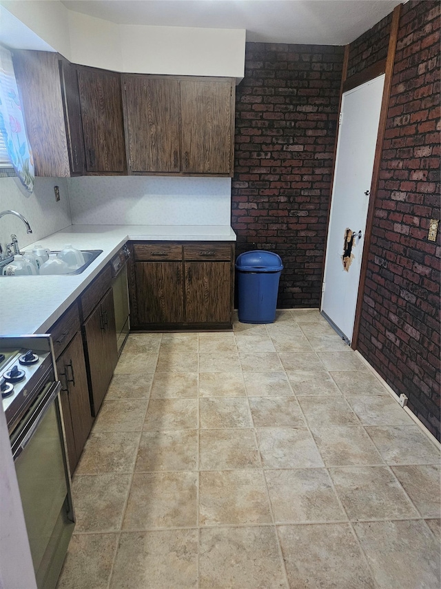 kitchen featuring range with electric cooktop, a sink, brick wall, light countertops, and dark brown cabinets