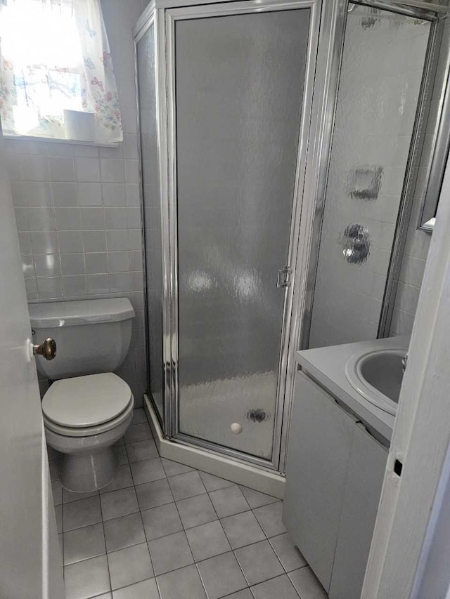 full bath with tile patterned floors, vanity, tile walls, and a shower stall