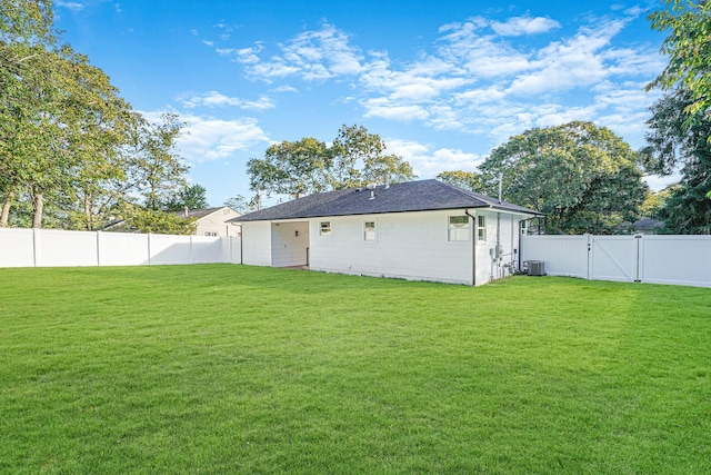 rear view of house featuring a fenced backyard, central AC unit, a yard, and a gate