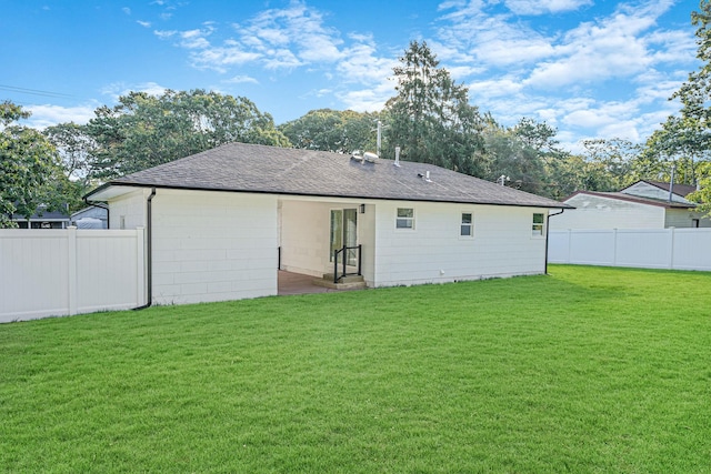 rear view of property featuring a patio area, fence private yard, a yard, and roof with shingles