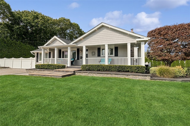 view of front facade with a front yard, fence, and covered porch