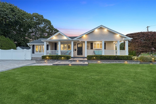 view of front of property featuring a lawn, a porch, and fence