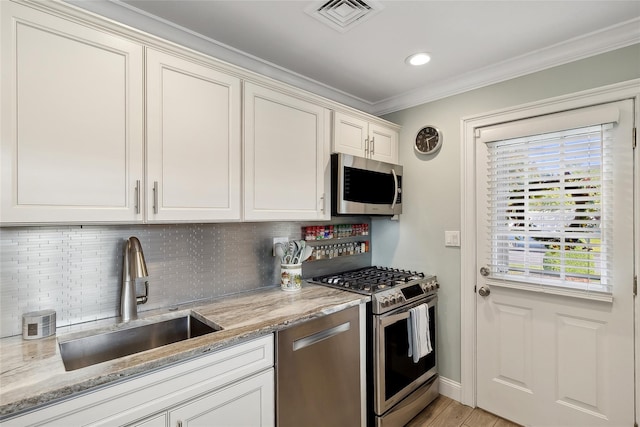 kitchen featuring visible vents, a sink, decorative backsplash, appliances with stainless steel finishes, and crown molding