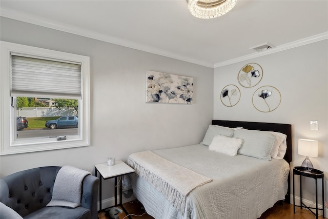 bedroom featuring wood finished floors, visible vents, baseboards, and ornamental molding