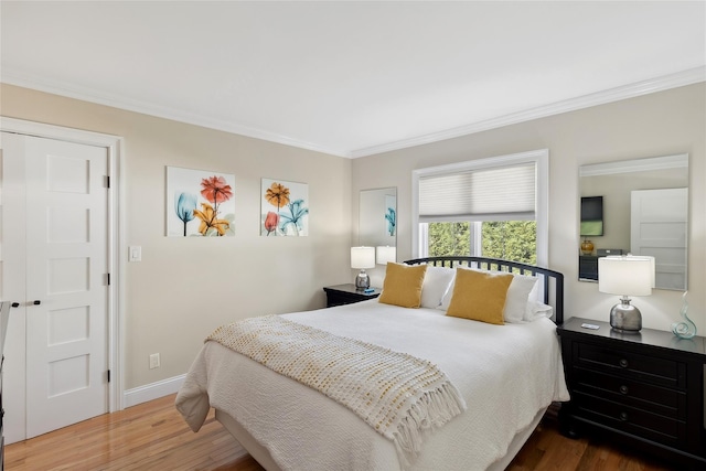 bedroom with crown molding, wood finished floors, and baseboards