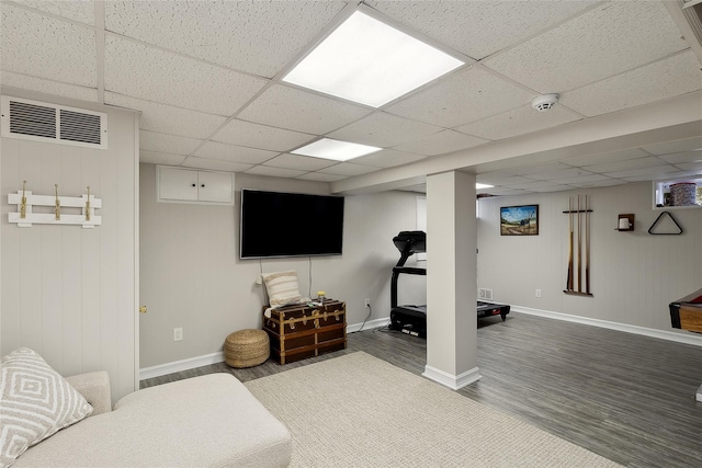 finished below grade area featuring wood finished floors, visible vents, a drop ceiling, and baseboards