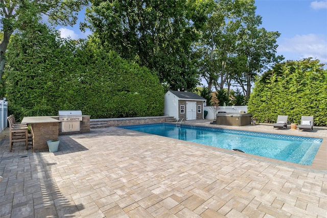 view of swimming pool featuring a shed, a fenced backyard, an outbuilding, an outdoor kitchen, and a patio