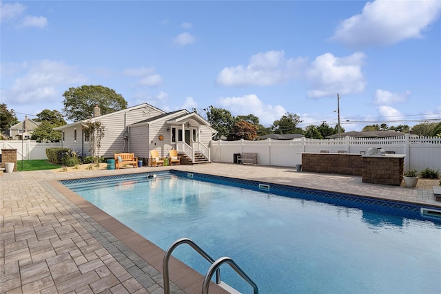 view of swimming pool featuring outdoor dry bar, entry steps, a fenced backyard, and a patio