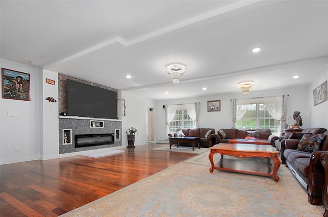 living area featuring recessed lighting, a fireplace, baseboards, and wood finished floors