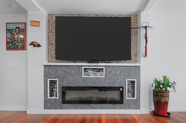 details with baseboards, wood finished floors, and a glass covered fireplace