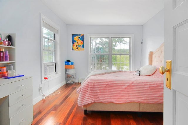 bedroom with wood finished floors, baseboards, and a baseboard radiator