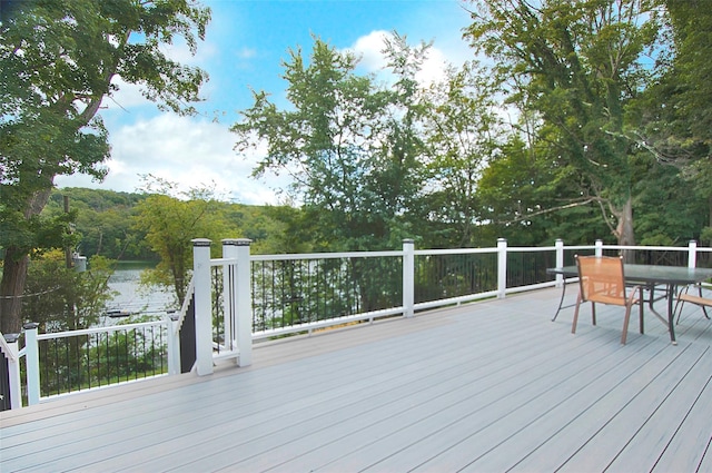 deck with outdoor dining space and a forest view