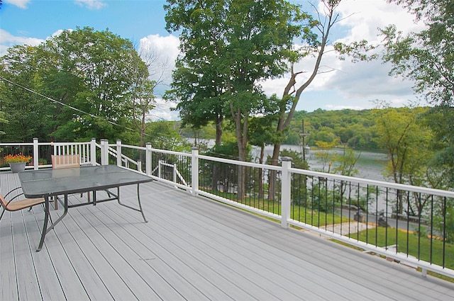 deck with a water view and outdoor dining space