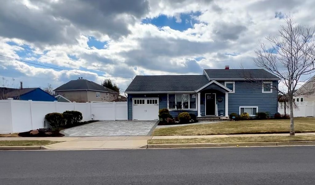 split level home with a garage, a front yard, driveway, and fence