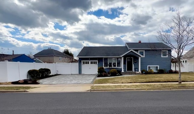 tri-level home with a garage, a front yard, driveway, and fence