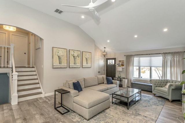 living room with visible vents, stairs, vaulted ceiling, wood finished floors, and a ceiling fan