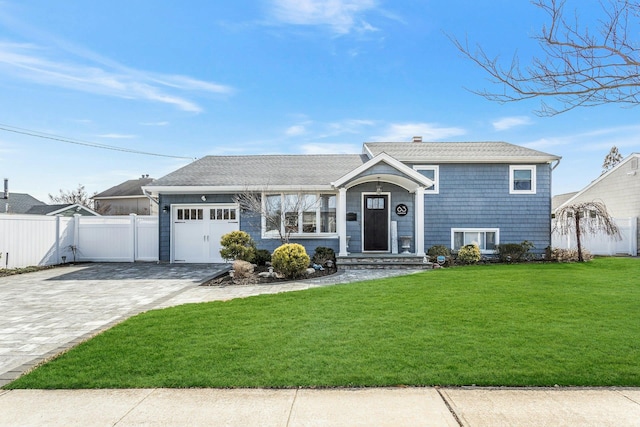 split level home with an attached garage, decorative driveway, a front yard, and fence