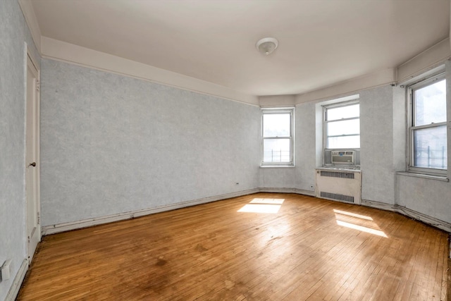 empty room featuring hardwood / wood-style flooring, radiator heating unit, and cooling unit