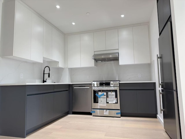 108-15 72nd Ave Unit 4D, Forest Hills, NY 11375 - kitchen featuring modern cabinets, light countertops, gray cabinets, appliances with stainless steel finishes, and exhaust hood