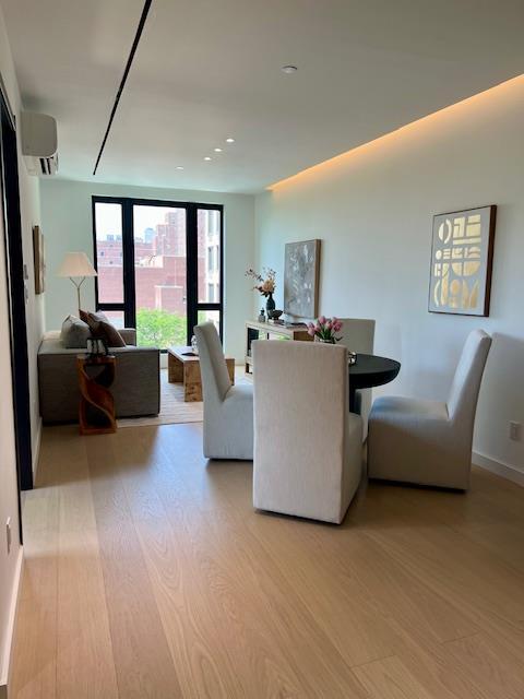 108-15 72nd Ave Unit 4D, Forest Hills, NY 11375 - living area with light wood-style floors, baseboards, and a wall mounted AC