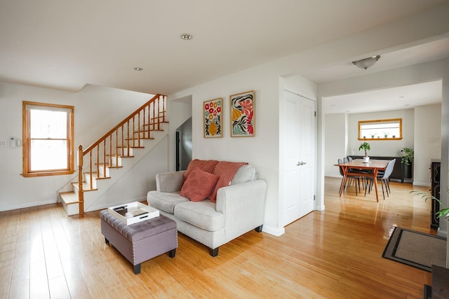 living room featuring a wealth of natural light, stairway, and light wood-type flooring