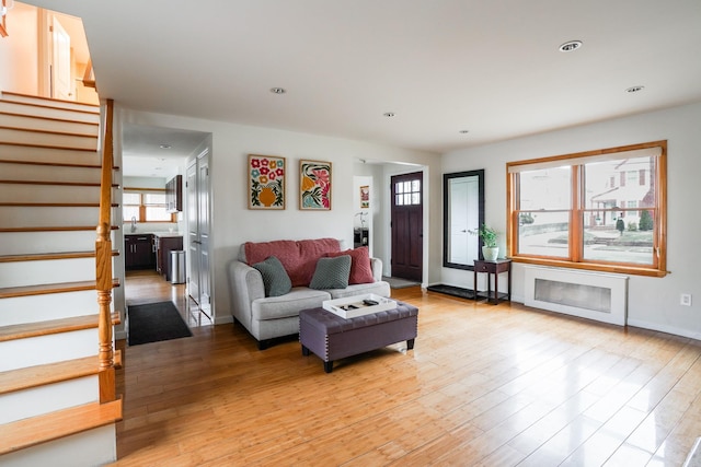 living room with recessed lighting, baseboards, light wood-style flooring, and stairs