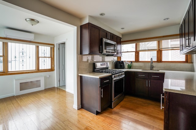 kitchen with a sink, appliances with stainless steel finishes, a wall mounted air conditioner, and light countertops