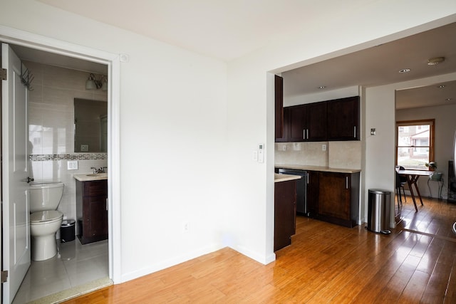 interior space featuring tasteful backsplash, dark brown cabinetry, dishwasher, light countertops, and light wood-style floors